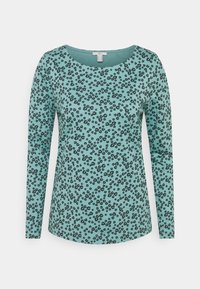 Turquoise lange mouwen top van zacht materiaal, met een zwart bloemenpatroon over de hele stof en een ronde halslijn.