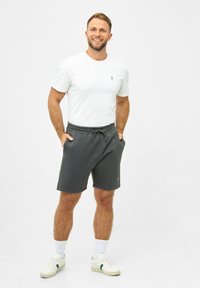 Gray cotton shorts with elastic waistband and drawstring, paired with a plain white T-shirt. Model wears white sneakers and crew socks.