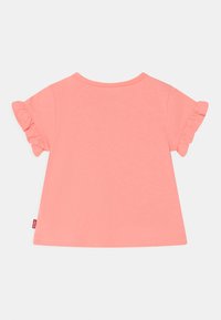 Camisa de manga curta em tom pêssego, com mangas franzidas, decote redondo e bainha curva. Feita de material de algodão macio e leve.