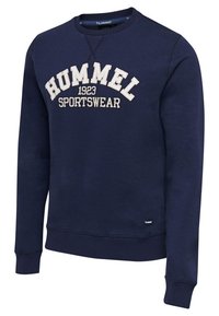 Námořnická mikina s kulatým výstřihem vyrobená z příjemné směsi bavlny, s logem "HUMMEL 1923 SPORTSWEAR" v světle béžové barvě, s žebrovanými manžetami a spodním lemem.