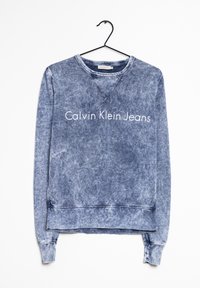 Blekt blå sweatshirt gjord av bomullsmix, med ribbade mudd- och fållkanter, med texten "Calvin Klein Jeans" tryckt över framsidan.