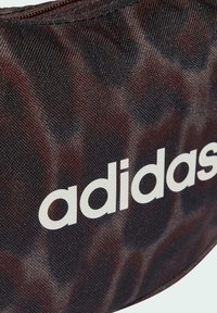 Czarny i brązowy woreczek z teksturowanej tkaniny z wyraźnym białym logo „adidas”. Okrągły kształt z zaokrąglonymi krawędziami i przeszyciami.
