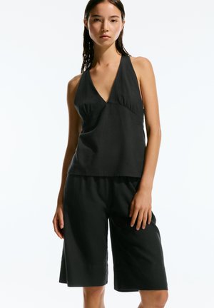 Black linen tank top with a deep V-neck and gathered detail, paired with matching loose-fitting shorts that reach mid-thigh.