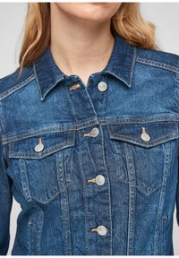 Chaqueta de mezclilla en azul oscuro con un diseño clásico. Cuenta con botones plateados, dos bolsillos frontales y detalles de costura visibles.