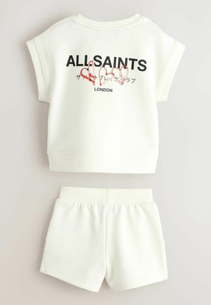 Baltos spalvos trumpomis rankovėmis džemperio ir šortų komplektas su užrašu „ALLSAINTS LONDON“ ir trimis raudonomis kontūrinėmis širdelėmis priekyje ant džemperio.