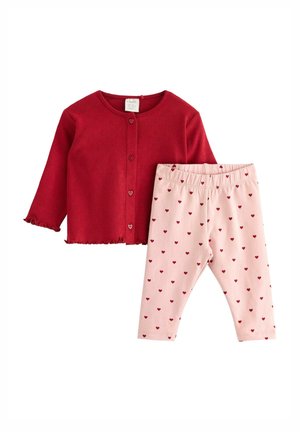 Rød cardigan med hjerteformede knapper og bølget kant, parret med lyserøde leggings med hjerte mønster i rød. Begge er lavet af blødt stof.