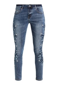Un jean slim en denim bleu présente une broderie florale le long des coutures latérales agrémentée de perles décoratives. Le tissu a un lavage moyen et une légère élasticité.