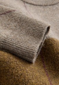 Woolen sweater in brown tones with a ribbed cuff, featuring a soft texture and a subtle maroon stripe on a darker brown base.