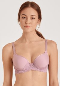Lichtroze bh met gladde cups en delicate kantdetails op de band, verstelbare bandjes en een haaksluiting aan de voorkant.