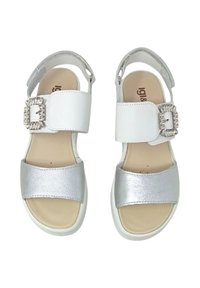 Sandali bianchi e argento con tomaia texturizzata, fasce larghe e fibbia decorativa. Suola piatta di colore chiaro e con dettagli minimi.