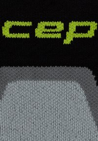 Tessuto di maglia nera con testo verde lime "cep" sopra un motivo curvo grigio e grigio chiaro.