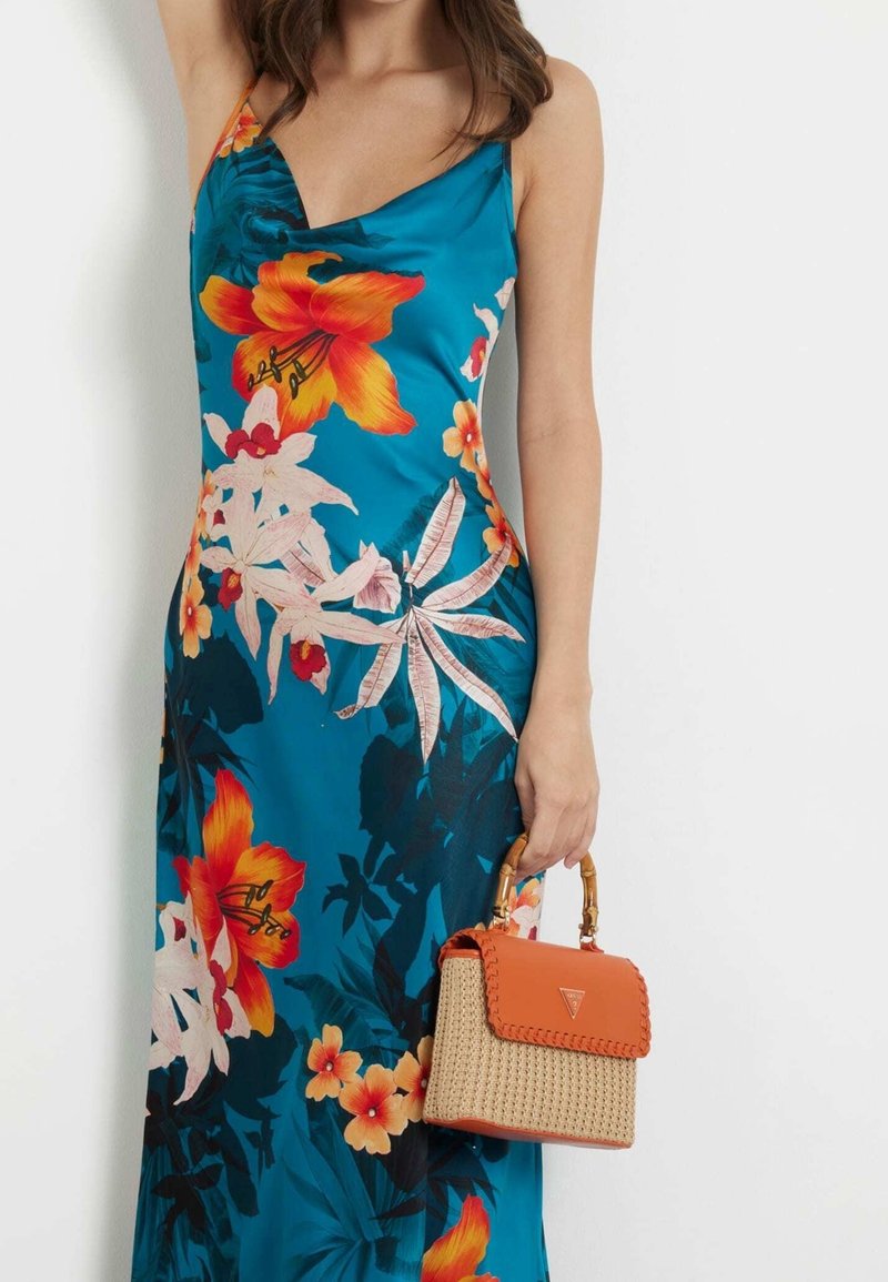 Turkoosi kukallinen maksimekko, jossa on oransseja ja vaaleanpunaisia kukkia. Pieni kudottu käsilaukku oransseilla yksityiskohdilla ja bambukahvalla.