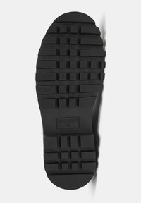 Čierna gumená podrážka topánky s textúrovaným vzorom protišmyku, obsahujúca obdĺžnikové a štvorcové vrypy. Označená nápisom "PULL & BEAR 42."