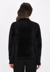 Sort fuzzy sweater med høj krave, lange ærmer og en struktureret overflade. Bagsiden har et blødt, voluminøst udseende.