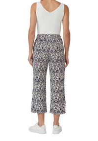 Wydrukowane, skrócone spodnie w kolorze granatowym i kremowym z nadrukiem liści, z elastycznym pasem. Połączone z białymi trampkami, ukazującymi luźny krój.