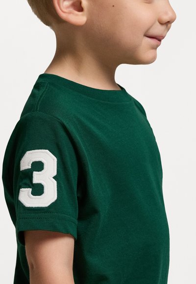 Grön bomullströja med ribbad rundhals och korta ärmar, med en stor vit siffra "3" broderad på vänster ärm.