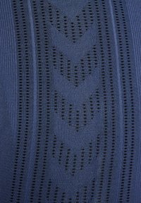 Marinblått stickat tyg med svarta mönster, där växelvis ränder och prickmönster skapar en texturerad yta.