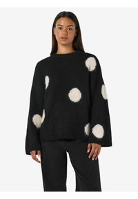 Suéter negro hecho de material esponjoso, con grandes lunares de color crema, mangas largas y un corte relajado.