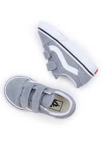 Grå mockaskor med vita accenter och kardborreband. Rundad tå, svart gummisula med vita detaljer. Logotyp synlig inuti.