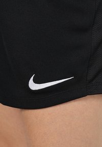 Shorts deportivos negros con un acabado texturizado y un logotipo bordado de Nike en blanco en la parte inferior izquierda.