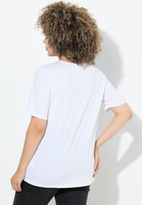 Camiseta blanca de manga corta en una tela suave y ligera, con un corte holgado y escote redondo, con una textura suave y un diseño minimalista.