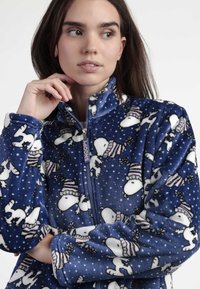 Chaqueta de forro polar azul con cremallera frontal, cuello alto y un patrón de Snoopy vestido de invierno con copos de nieve en todo el diseño.