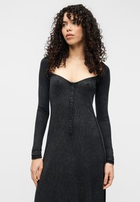 Φόρεμα μακρυμάνικο σε σκουρό γκρι ριμπ ύφασμα με εφαρμοστό μπούστο, βαθύ V-λαιμόκοψη και λεπτομέρεια με κουμπιά κατά μήκος του κέντρου.