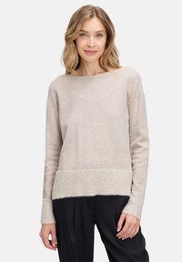 Beżowy sweter z dzianiny z teksturowanym dolnym wykończeniem i mankietami. Luźny krój z szerokim dekoltem i prążkowanymi akcentami na rękawach i dolnym wykończeniu.