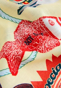 Material texturat cu imprimeu roșu, fundal crem și accente verzi. Include modele stilizate, text și suprafață texturată.