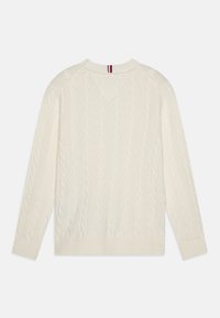 Maglione color crema a maglia a cables con scollatura a V, polsi e orlo a coste. Presenta un accento a righe sul colletto posteriore.