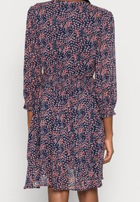 Blumenkleid mit navyfarbenem Grund und pinken Blumen, langen Puffärmeln, elastischem Bund und ausgestelltem Saum. Leichter, semi-transparenter Stoff.