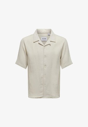 Camicia a maniche corte di un beige chiaro, con tessuto strutturato, chiusura con bottoni e colletto classico. Etichetta visibile all'interno del colletto.