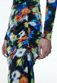 Figurbetontes Kleid mit buntem, abstraktem Druck. Verfügt über Raffungen an der Seite und ein verstellbares Band am Saum. Weicher, dehnbarer Stoff.