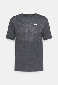 Szara koszulka sportowa z miękkiego materiału, z teksturowaną górną częścią, okrągłym dekoltem, krótkimi rękawami oraz białym logo Nike na piersi.
