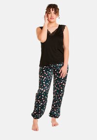 Haut sans manches noir avec un motif en dentelle au niveau du col ; pantalon noir ample avec un motif floral sur un fond sombre.