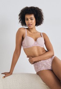 Light pink lace bra with scalloped edges and matching lace underwear, featuring a smooth design and intricate floral patterns.