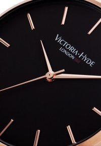 Black watch face with rose gold hour markers and hands. Features brand name "Victoria Hyde London" in silver. Circular case design.