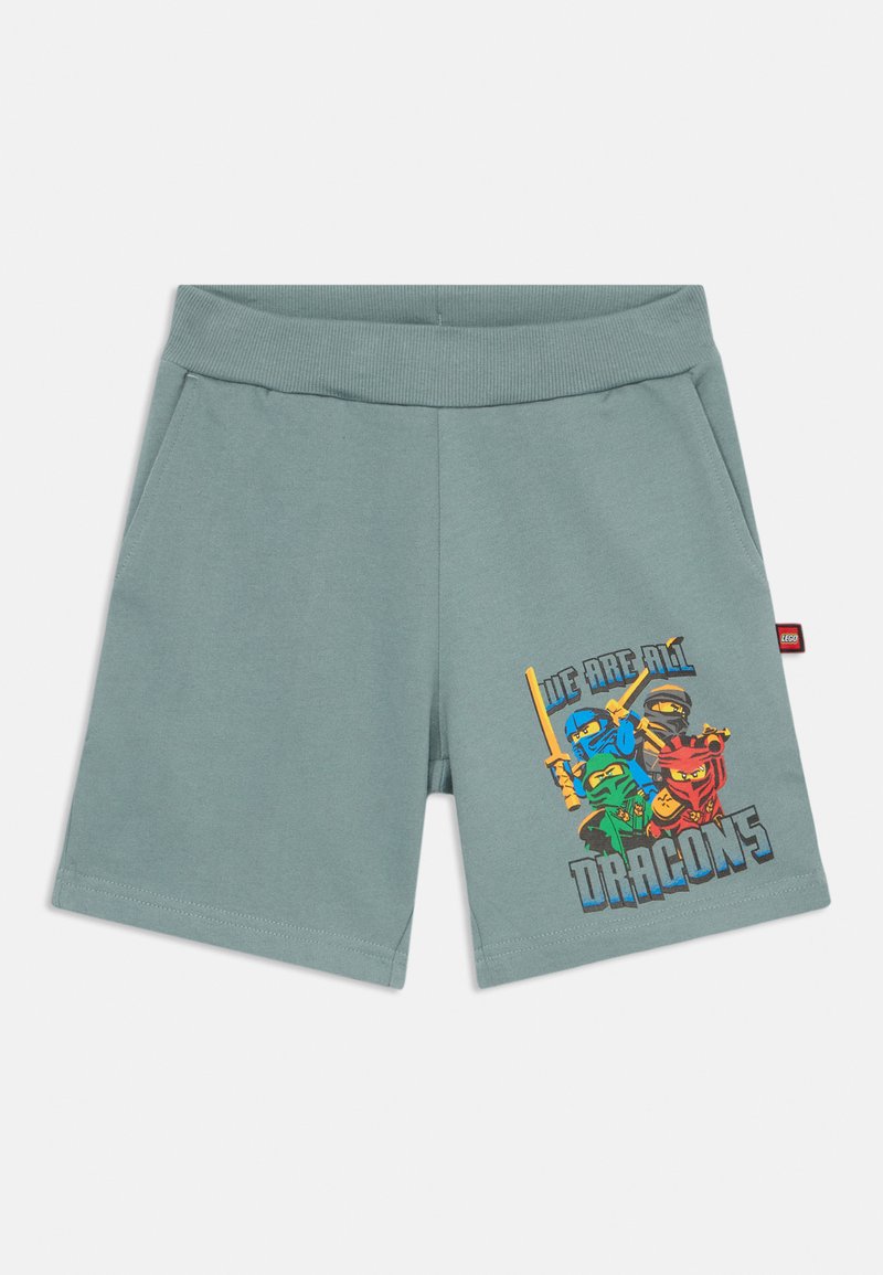 Grau-grüne Shorts aus weichem Stoff, mit einem bunten Grafikdesign von Charakteren und dem Text "WIR SIND ALLE DRACHEN" auf der Vorderseite.