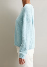 Ljust blå oversized tröja med strukturerad stickning, ribbade cuffs och nederkant. Korta, lös passande ärmar ger en avslappnad silhuett.