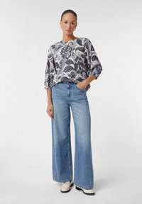 Bluse mit Blumenmuster in Hellblau und Weiß, mit rundem Ausschnitt und Dreiviertelärmeln, kombiniert mit weit geschnittenen hellen Jeans.