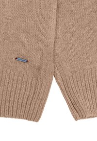 Beżowy sweter z dzianiny o prążkowanej strukturze. Posiada małą niebieską metkę z czerwonymi akcentami. Otwarty przód, półstrukturalny design.