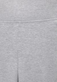 Gros plan sur un tissu gris, présentant une texture lisse et douce avec un motif côtelé en haut et une couture plate. Couleur uniforme sans accents visibles.