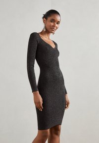 Black fitted dress with long sleeves, ribbed texture, and a deep V-neck. Decorated with subtle metallic threads for added detail.