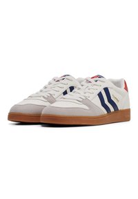 White athletic shoes with blue and red accents. Features a suede toe cap, rubber sole, and a smooth leather upper. Logos on sides and tongue.