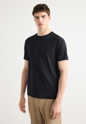 Black cotton t-shirt with a crew neck and short sleeves, featuring a subtle embossed logo on the left chest and a straight hem.