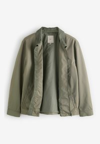 Chaqueta ligera verde con un exterior suave, cuello alzado, cierre de cremallera y un sutil detalle de costura, sin forro y con bolsillos laterales.