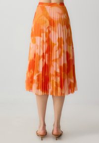 Faltender Midirock im Orange- und Pink-Ombre-Muster, gefertigt aus leichtem Stoff. Verfügt über einen glatten Bund und transparente Textur.