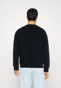 Felpa nera realizzata in un tessuto morbido, con scollo rotondo e polsini a costine. La parte posteriore presenta un design semplice e pulito, senza motivi.