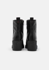 Black ankle boots made of smooth leather, featuring a high block heel, zip closure, and decorative stitching on the sides.