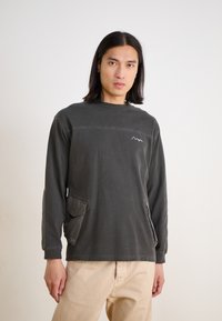 Dark gray long-sleeve shirt with crew neck, featuring a mountain logo, side pockets, and contrasting stitching on the shoulders.